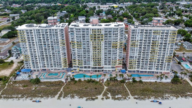 A high-rise hotel with multiple balconies, a pool area, and beachside amenities.