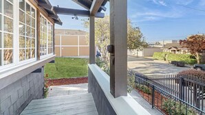 A residential porch with a covered area, a small garden, and a view of the street.