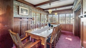 A dining room with a long wooden table, multiple chairs, and a large window with a view.