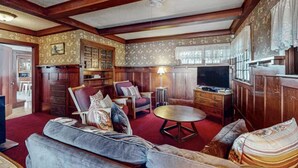 A traditional living room with a sofa, armchairs, a coffee table, and a television.