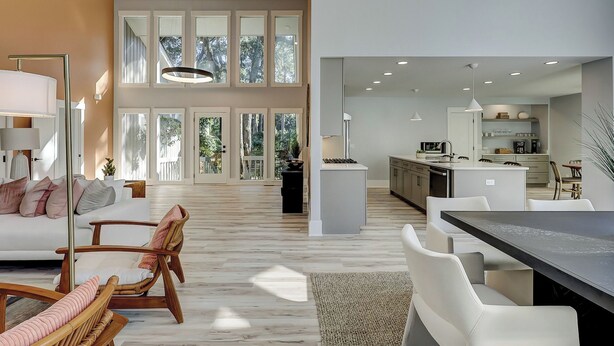 A spacious living area with a large window, a dining table, and a kitchen area with modern appliances. - Sunset Rentals | Red Oak 40 (Hilton Head Island)