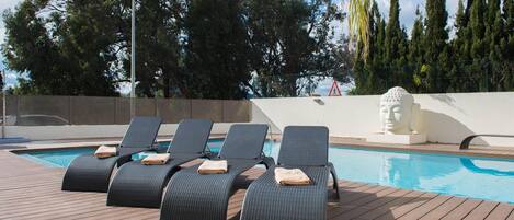 A poolside area with lounge chairs and a statue.
