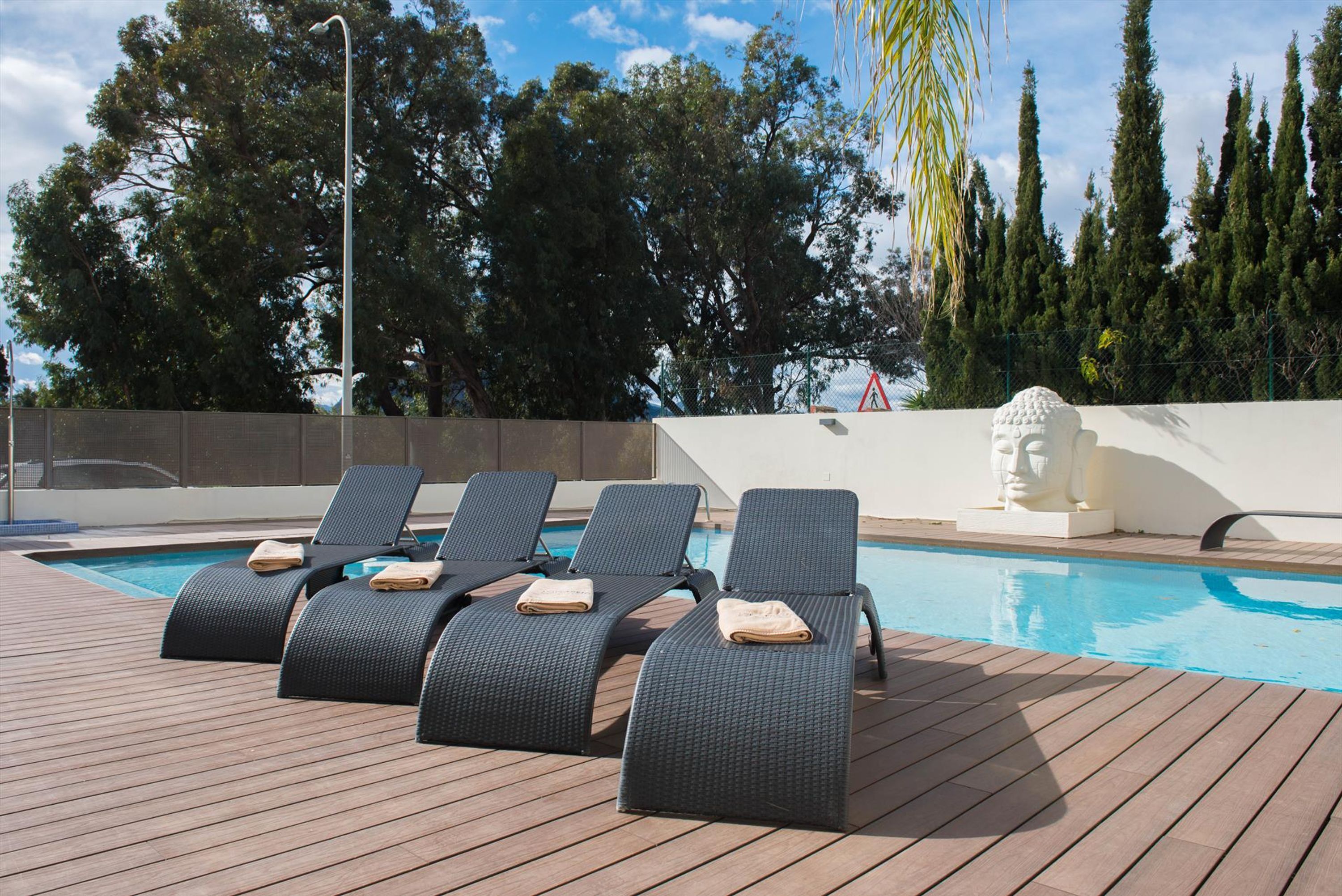 A poolside area with lounge chairs and a statue.