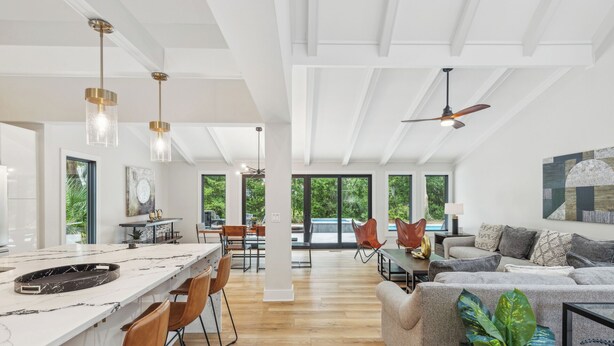 A spacious living area with a large sofa, a dining table, and a kitchen with a marble countertop. - Sunset Rentals | Planters Wood 48 (Hilton Head Island)