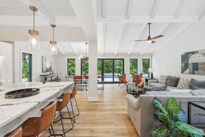 A spacious living area with a large sofa, a dining table, and a kitchen with a marble countertop. - Sunset Rentals | Planters Wood 48 (Hilton Head Island)