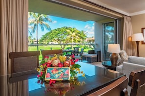 Une chambre d’hôtel avec balcon, une table agrémentée d’un arrangement floral et une vue sur un terrain de golf.
