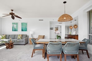 Un salon moderne comprenant un canapé, une table basse, une table à manger, des chaises et un ventilateur de plafond.