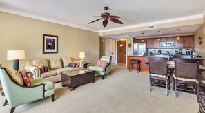 A living room with a sofa, chairs, a coffee table, and a kitchen area with a bar. - Honua Kai | Ocean View 6 BR, Sleeps 20 | Car Incl. w/ 6+ Nights | HKH ML-1085 by KBM (Lahaina)