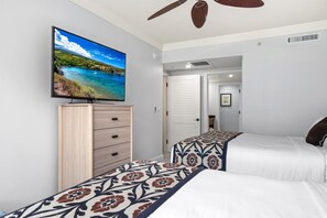 Een slaapkamer met twee bedden, een televisie op een kast en een plafondventilator.