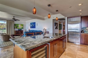 A modern kitchen with a marble countertop, stainless steel appliances, and pendant lighting.