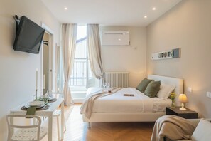 A modern hotel room with a bed, bedside table, and a mounted TV. - MT Studio 1 by Rent All Como (Como)