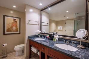 Une salle de bain d’hôtel avec deux lavabos, un grand miroir, une œuvre d’art encadrée au mur et des toilettes.