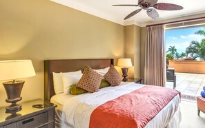 A hotel room with a bed, two bedside lamps, a ceiling fan, and a view of the outdoors.