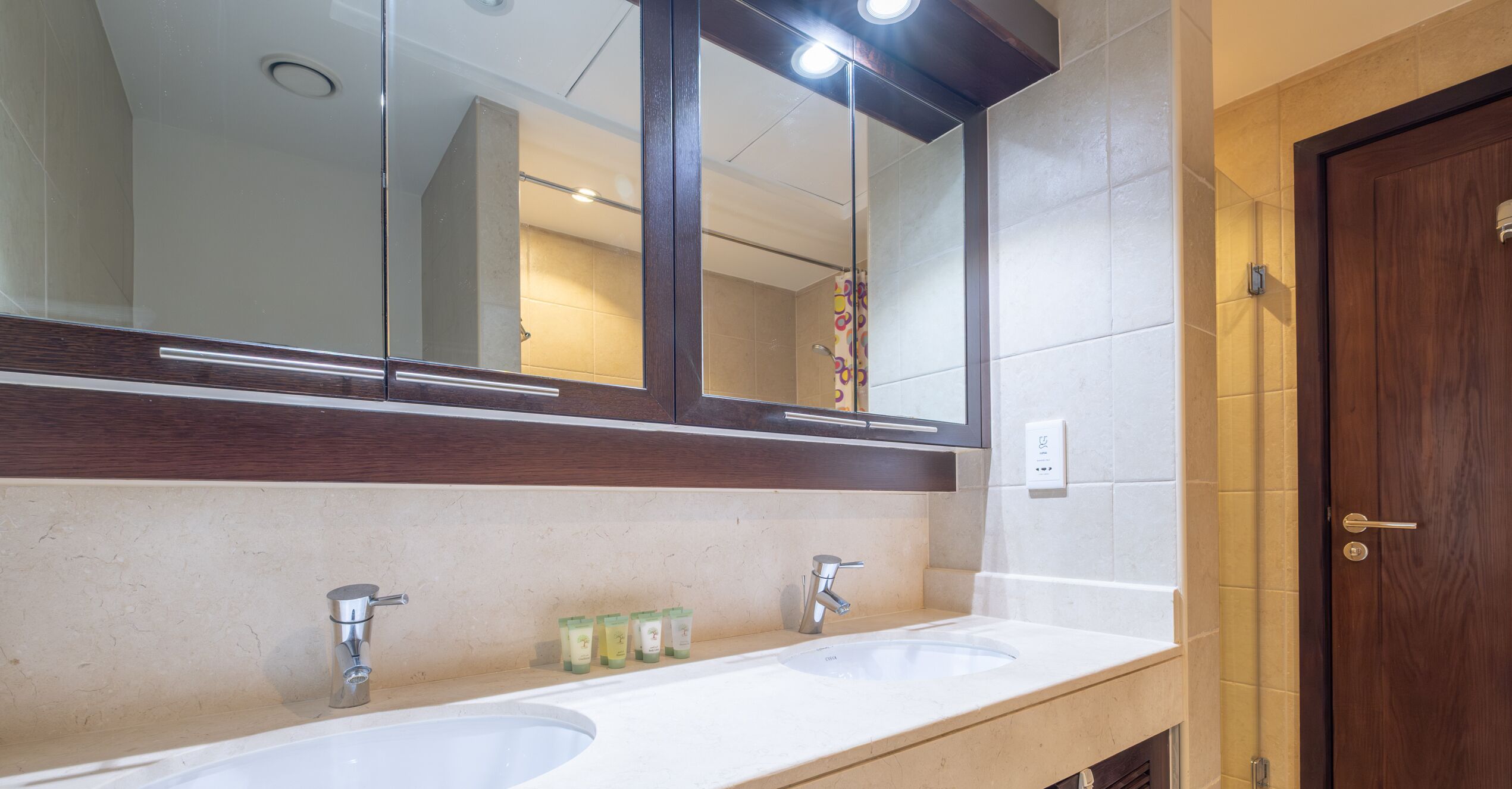 A bathroom with two sinks, a mirror, and a wooden door.