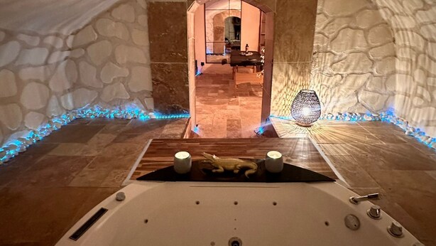 L’intérieur d’un hôtel de glace, avec une sculpture de glace centrale, des murs en pierre et un coin salon accueillant éclairé à la bougie.