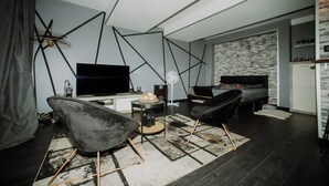Un salon moderne doté d’un téléviseur à écran plat, d’un canapé, d’un coin repas avec une table et d’un tapis à motifs.