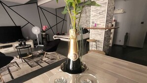 Un salon moderne avec un plancher en bois, un vase en verre contenant des fleurs et deux verres à vin posés sur une table.