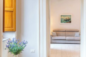 A modern living room with a beige sofa, a framed painting of a sailboat, and a potted plant. - Maramia Luxury Apartment (Sant'Agnello)