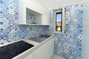 A compact kitchen with a sink, white cabinets, and blue patterned tiles. - Maramia Luxury Apartment (Sant'Agnello)