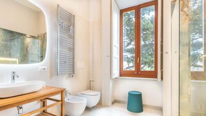 A modern bathroom with a large sink, bidet, and a window with a view of trees. - Maramia Luxury Apartment (Sant'Agnello)