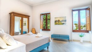 A bedroom with a bed, a bench, a mirror, a painting, and a window with a view. - Maramia Luxury Apartment (Sant'Agnello)