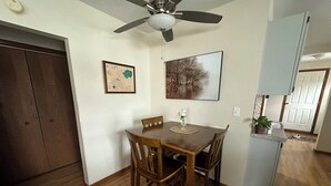 Un'area pranzo con un tavolo e sedie in legno, una ventola a soffitto, una mappa incorniciata e un quadro appeso al muro.