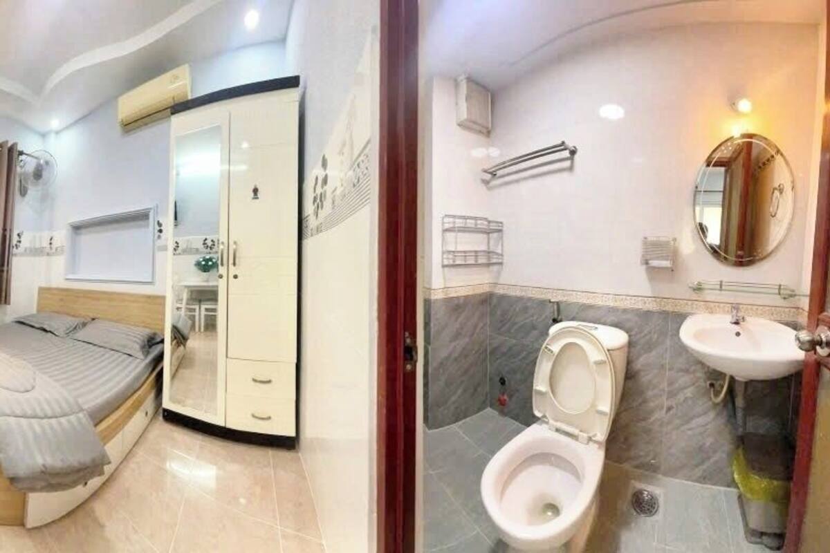 Ein Schlafzimmer mit Bett, Schreibtisch und Kleiderschrank. Das Zimmer verfügt über ein Badezimmer mit Toilette, Waschbecken und Spiegel.