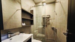 Ein modernes Badezimmer mit einer Duschkabine, einem weißen Waschbecken und einer Toilette.