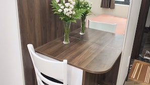 Ein Essbereich mit einem Holztisch, weißen Stühlen und einer Vase mit weißen Blumen.