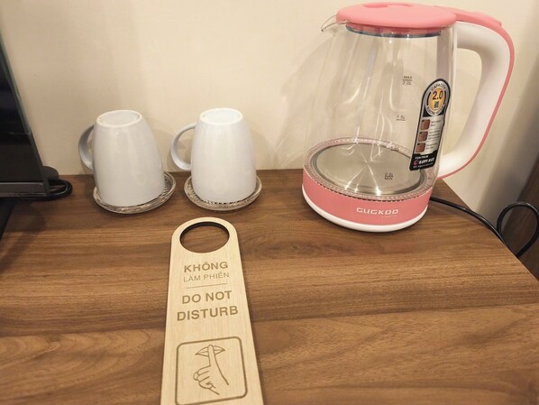 Eine Kaffeemaschine, zwei weiße Tassen und ein Holzschild auf einer Holztischplatte.