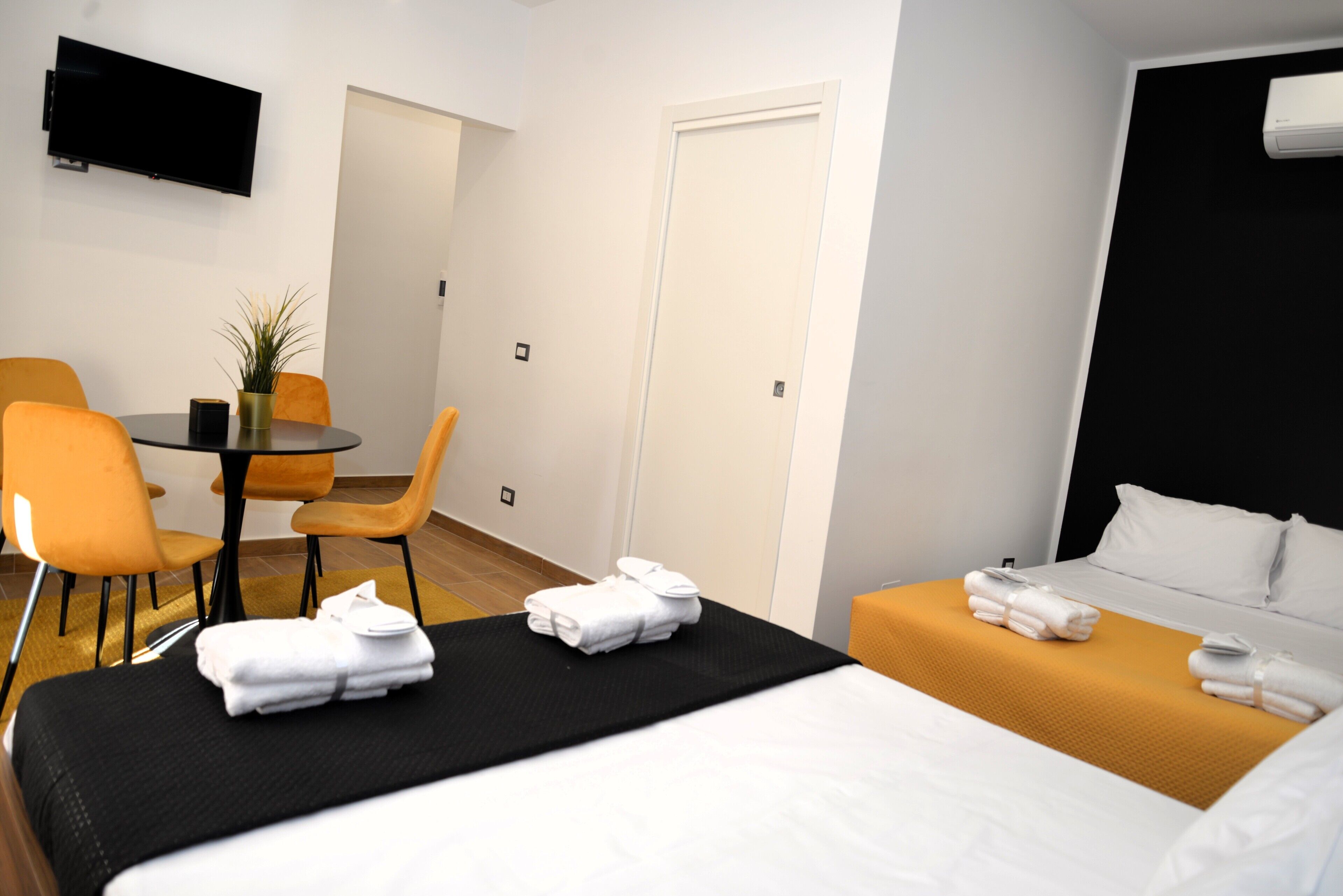Een hotelkamer met een bed, een bank, een eettafel met stoelen en een aan de muur bevestigde televisie.