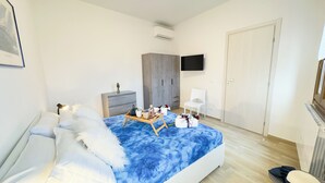 Une chambre à coucher avec un lit, une commode, un téléviseur et une armoire.