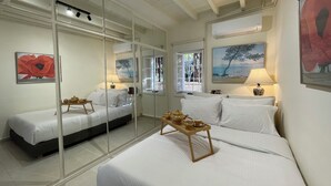 Een hotelkamer met twee bedden, een grote spiegel en kunstwerken aan de muren.
