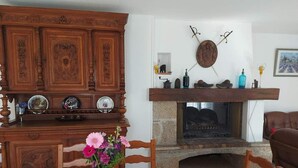 A dining area with a wooden cabinet, a fireplace, and a table with a floral tablecloth. - Olive trees (Tornac)