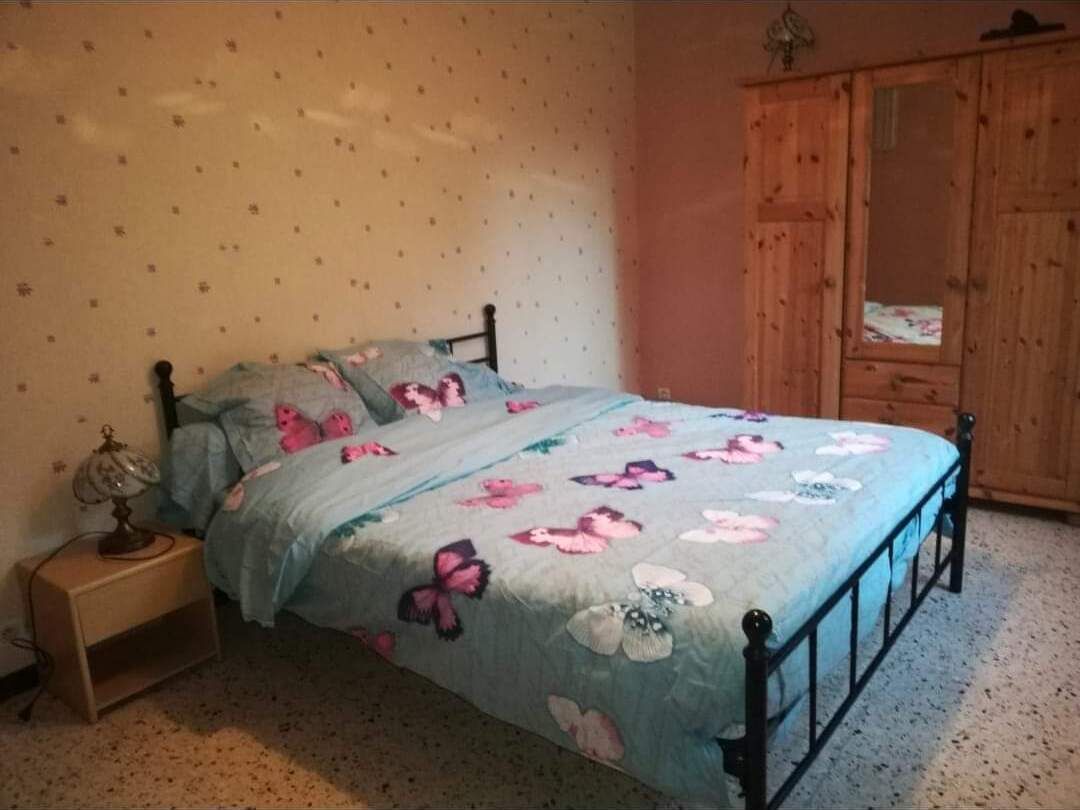 Un dormitorio con cama, mesita de noche, armario de madera y pared decorada.