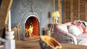A cozy room with a fireplace, a bed with patterned bedding, and wooden furniture.