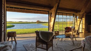 A room with a large window overlooking a lake, wooden flooring, and a rustic interior design.