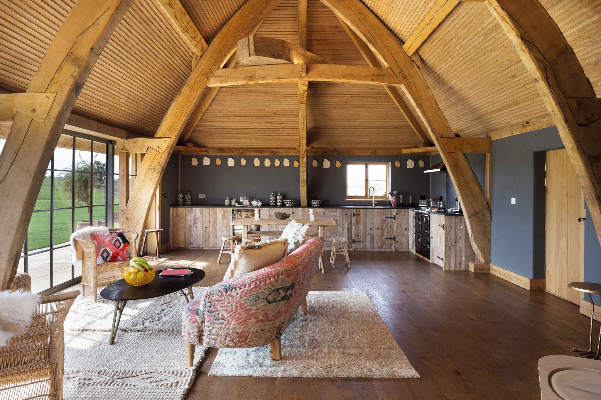 Un loft amplio con un alto techo de madera, una zona de cocina y un área de estar con una mesa y sillas.