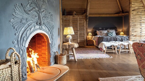 A cozy room with a fireplace, wooden furniture, and a bed with a patterned bedspread.