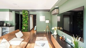 A modern living room with a sofa, coffee table, and a green vertical garden. - City Garden - A green setting in the heart of Dijon (3 stars) (Dijon)