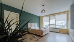 A bedroom with a bed, a window with blinds, a radiator, and a hanging light fixture. - Full Amenities, Modern 1BR • near Medpark Riscani (Chișinău)