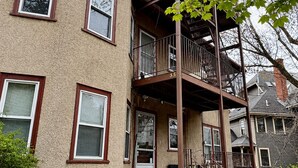 A multi-story building with a balcony, a door, and a window.