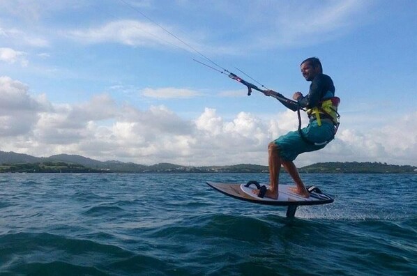 A person windsurfing on a body of water with hills in the background. - Town house 5 minutes from one of Martinique's best kitesurfing spots (Le Vauclin)