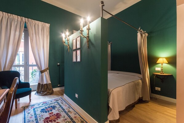 A room with a bed, a chair, a lamp, and a window with curtains. - Porta Palace Apartments (Turin)