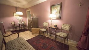 A living room with a wooden floor, a dining table with chairs, a sofa, a patterned rug, and a cabinet. - Porta Palace Apartments (Turin)