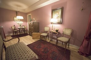 A living room with a wooden floor, a dining table with chairs, a sofa, a patterned rug, and a cabinet. - Porta Palace Apartments (Turin)