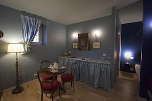 A dining area with a table set for four, a bar counter, and a kitchen area. - Porta Palace Apartments (Turin)