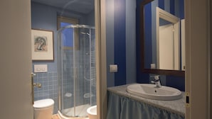 A bathroom with a glass-enclosed shower, a sink with a mirror, and a toilet. - Porta Palace Apartments (Turin)
