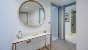 A hallway with a marble console table, a gold-framed mirror, and a door leading to another room. - Contemporary Marylebone with Pool and Gym AC (Greater London)