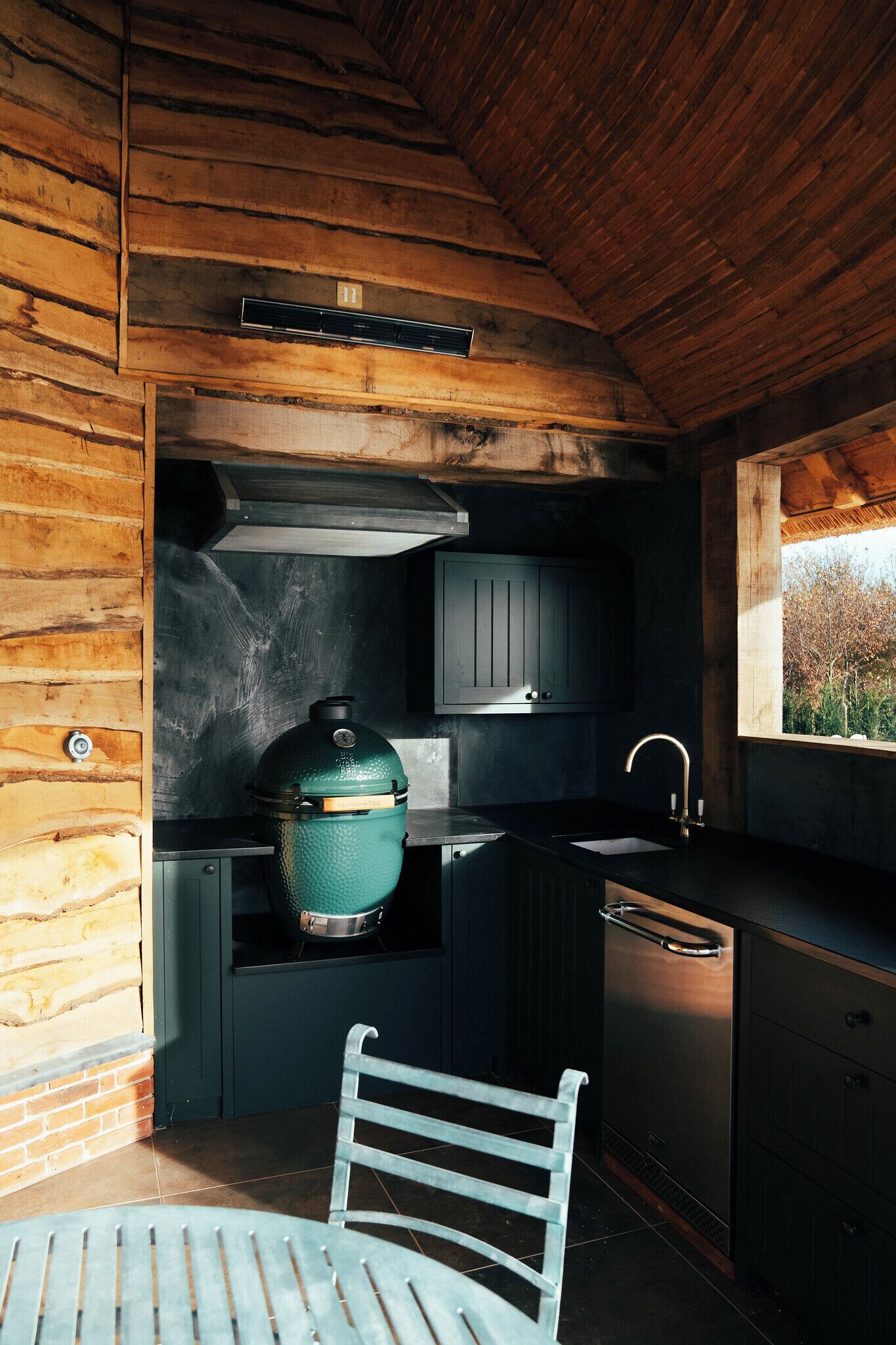 Una cucina compatta con una griglia integrata, un lavello e una finestra con vista su un paesaggio naturale.